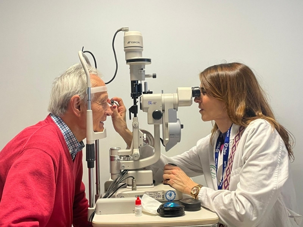 La Dra. Caban&aacute;s explorando a un paciente en la l&aacute;mpara de hendidura.